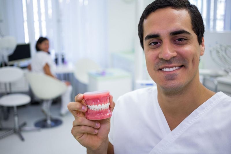 Dentista especializado em periodontia segurando um molde de uma boca em um consultório