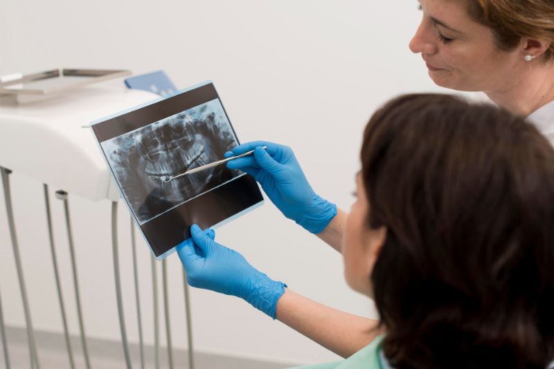 Dentista mostrando radiografia panorâmica para paciente.