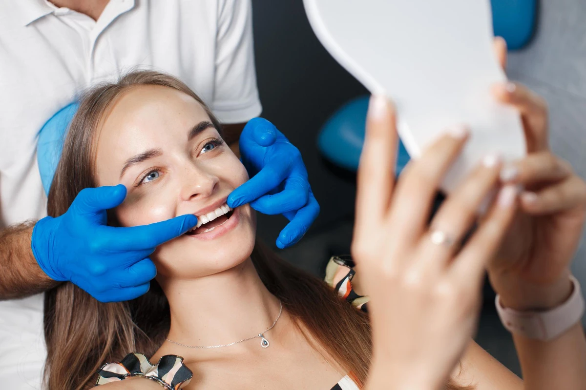 Dentista mostrando gengiva de paciente segurando espelho de mão.