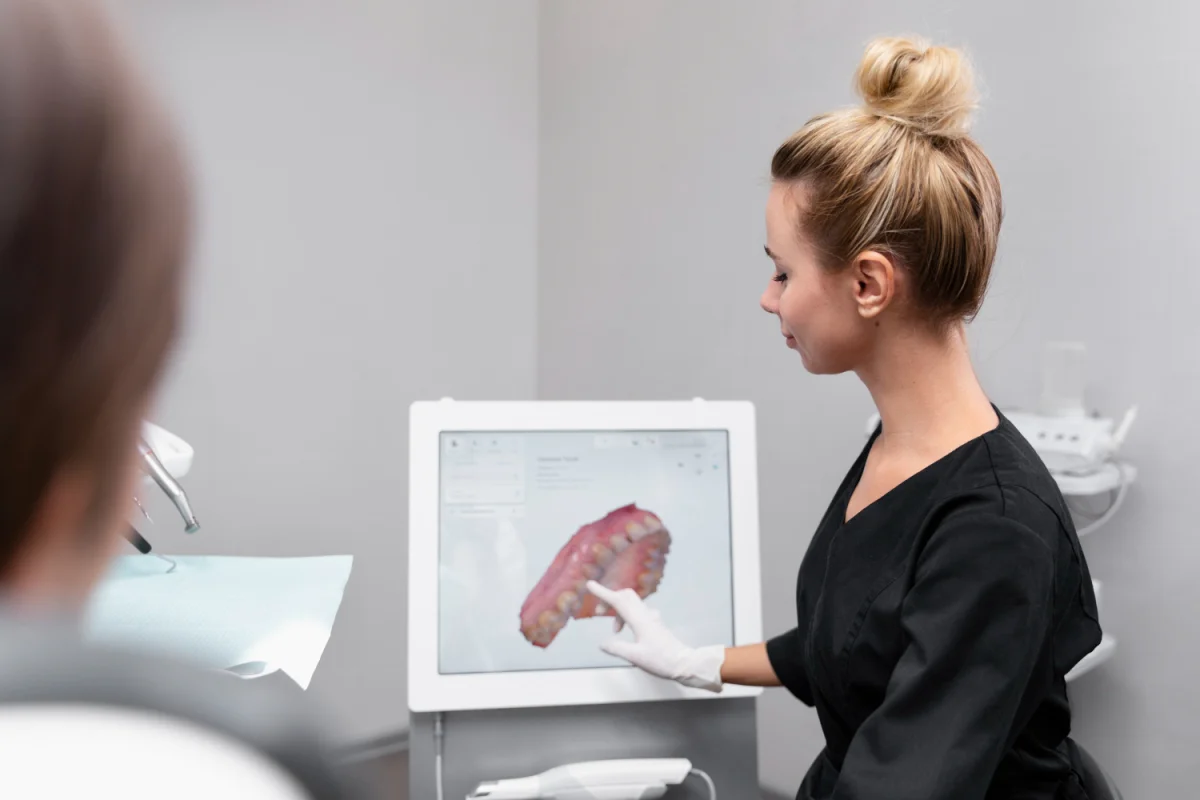 Dentista mostrando modelo 3D de arcada dentária em tela digital para paciente em consultório odontológico