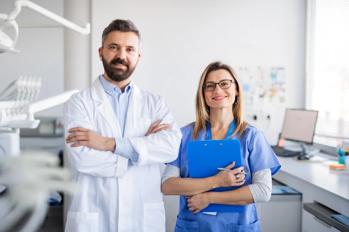 Dentistas sorridentes em consultório moderno.