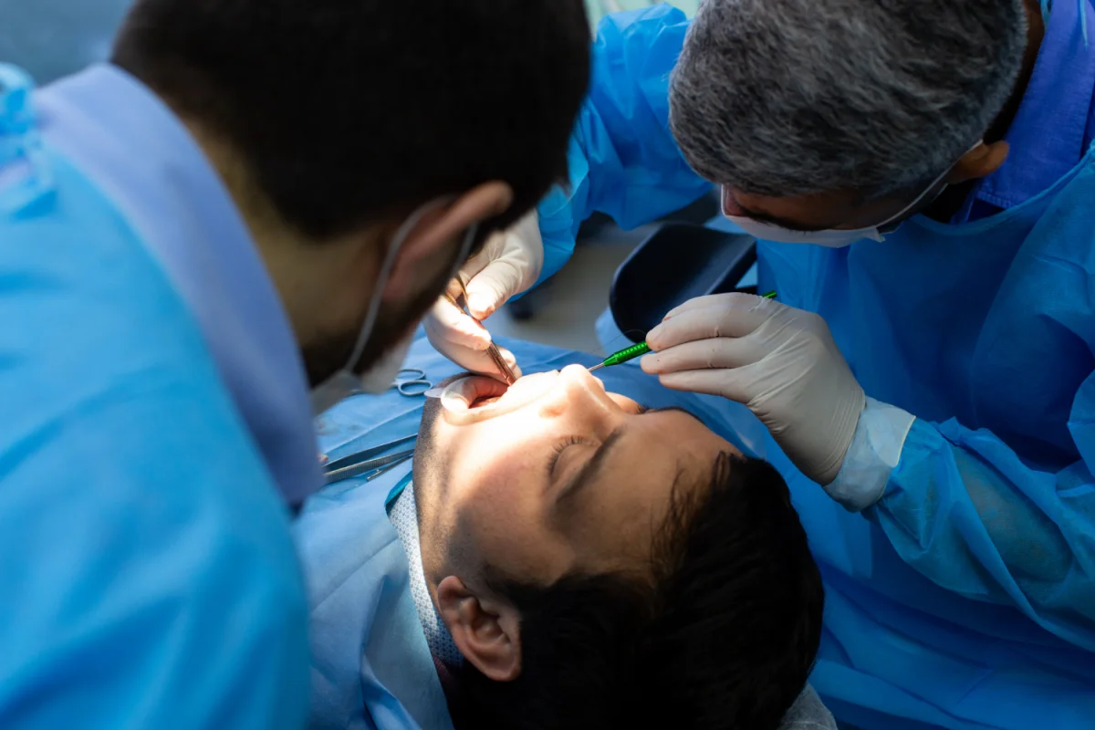 Dentista realizando procedimento odontológico em paciente com auxílio de dentista em clínica